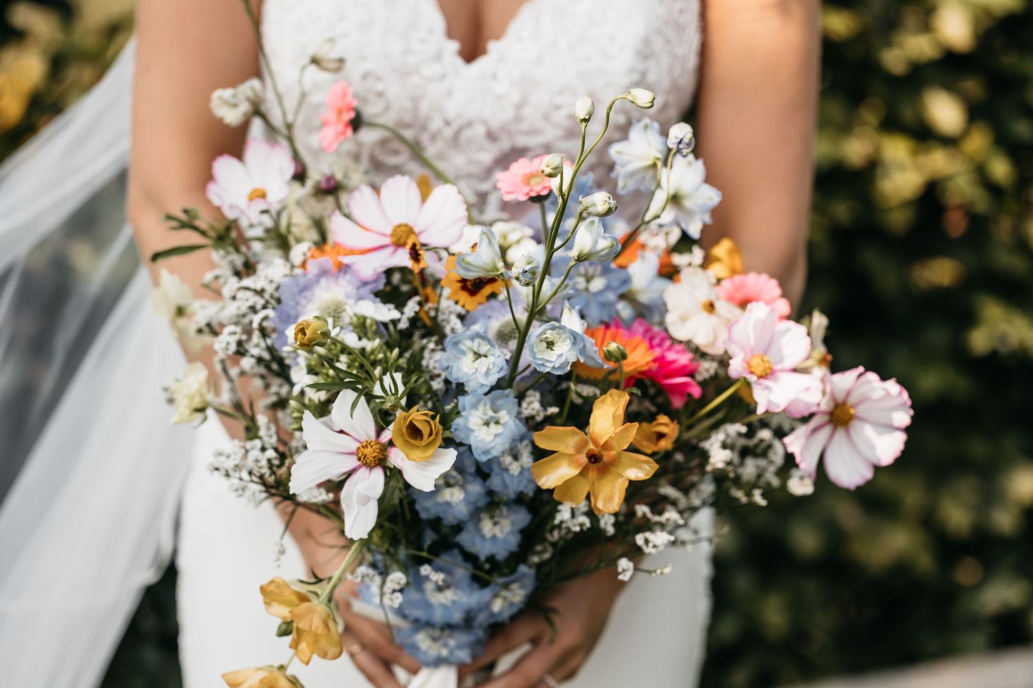 Close-up of bridal bouquet with pink, blue, yellow, and white wildflowers.