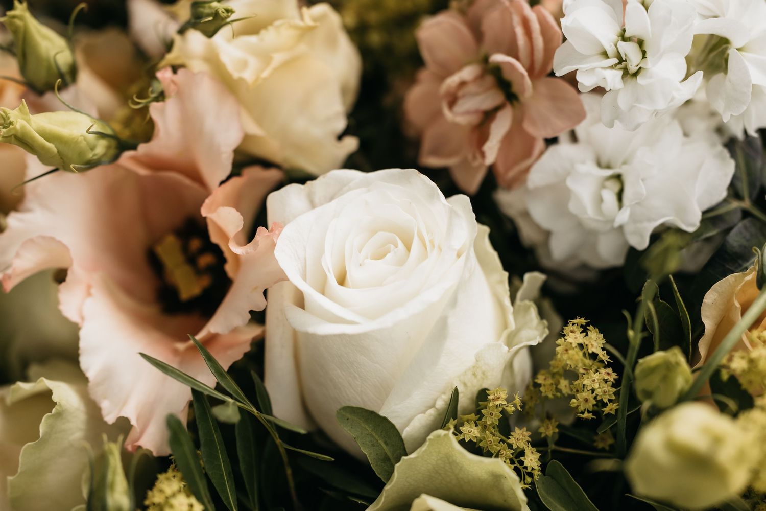 Close-up of elegant wedding bouquet featuring white roses and blush pink flowers.