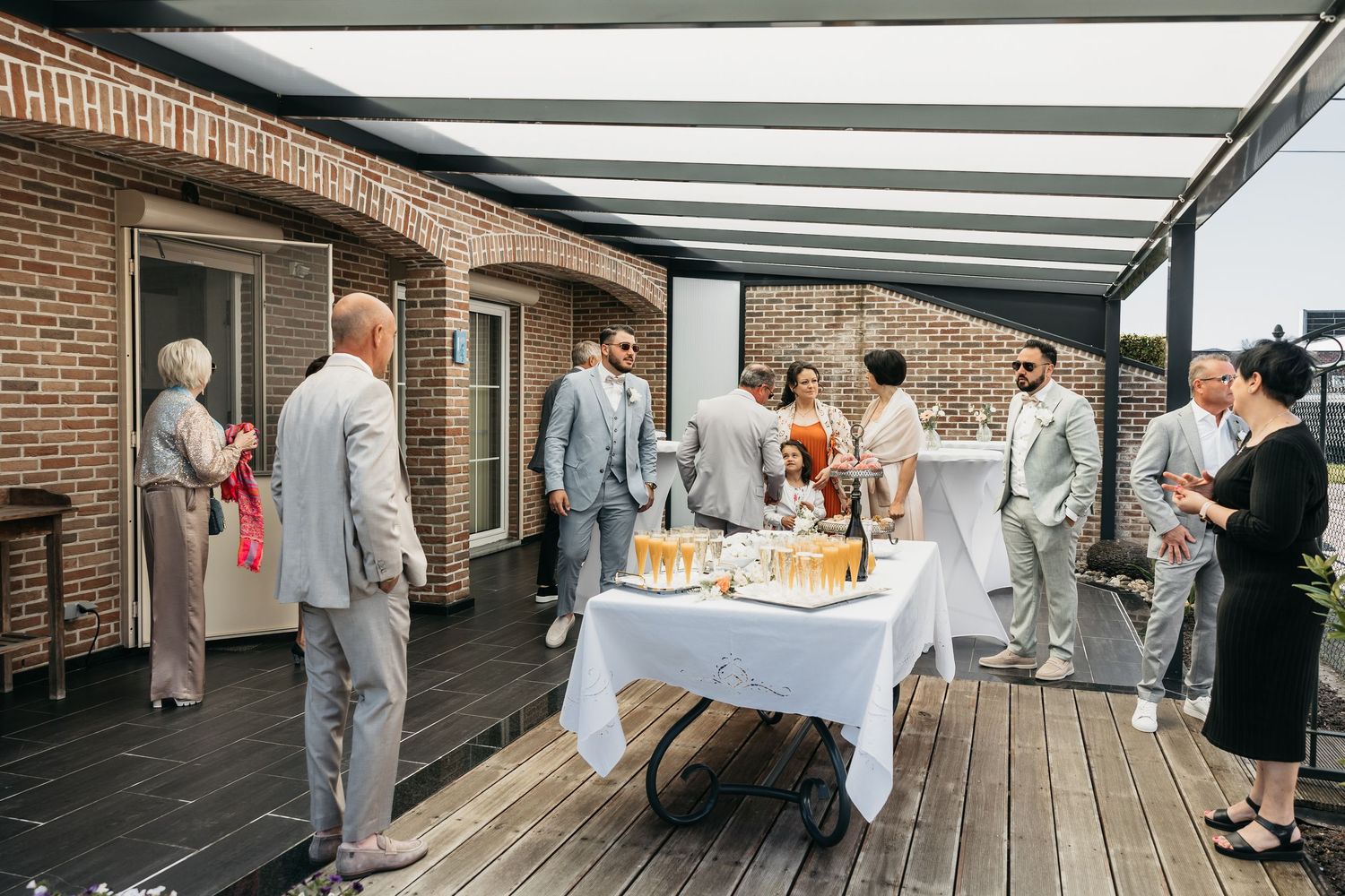 Wedding guests mingling on a rooftop terrace with champagne and cocktail tables.
