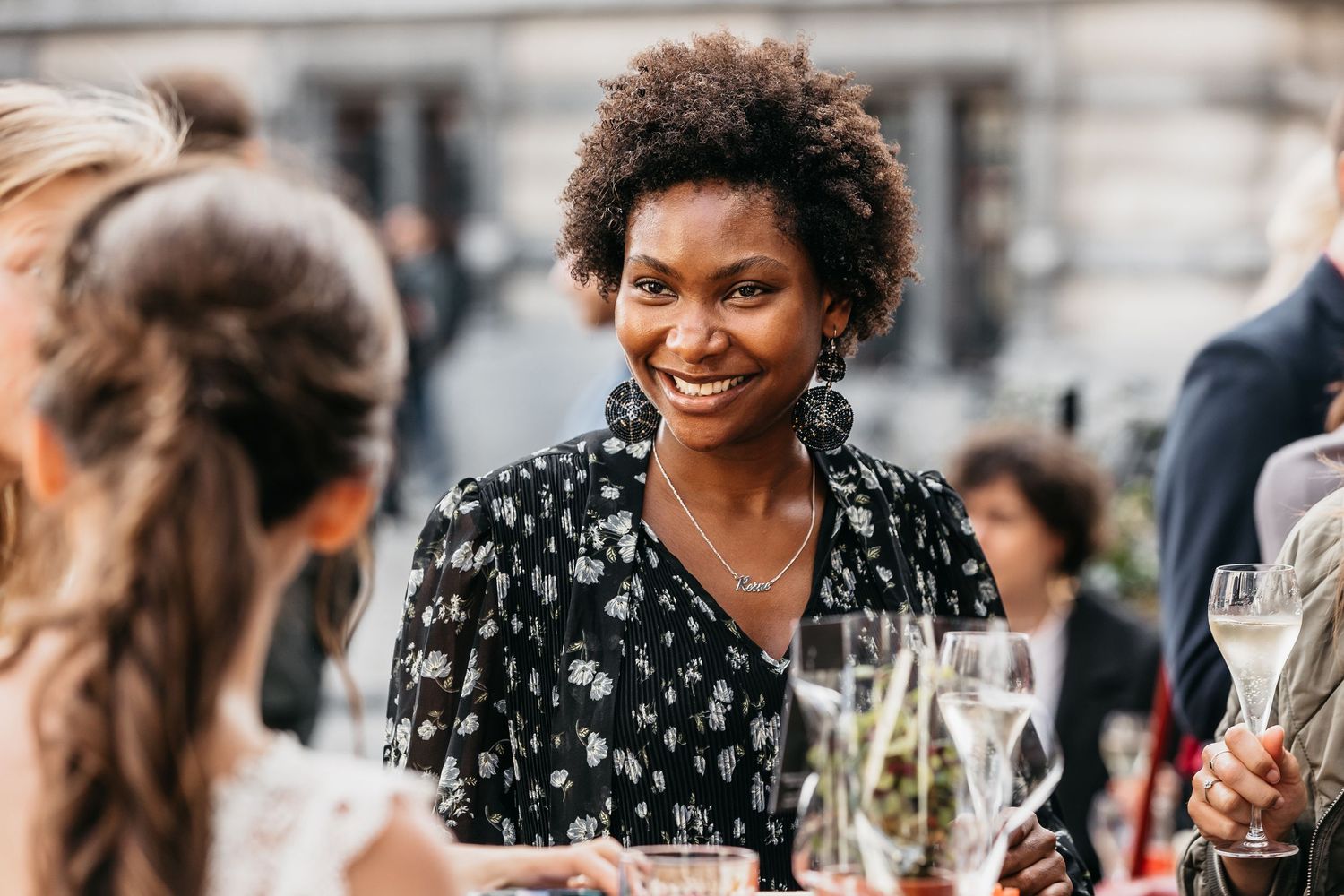 Smiling woman in floral dress socializing at an elegant outdoor wedding reception.