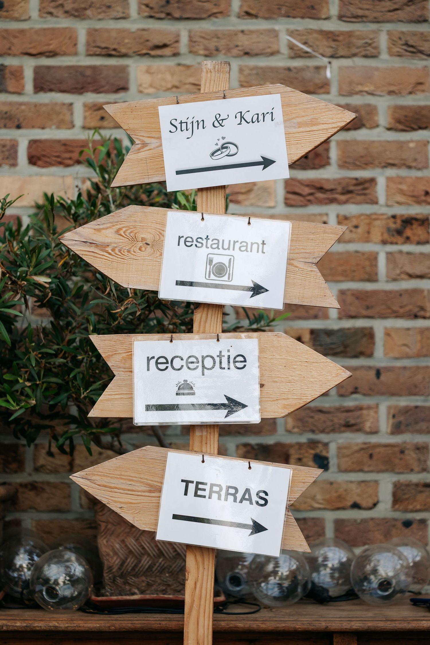 Wooden directional wedding sign for Stijn and Kari pointing to restaurant, receptie, and terras areas.