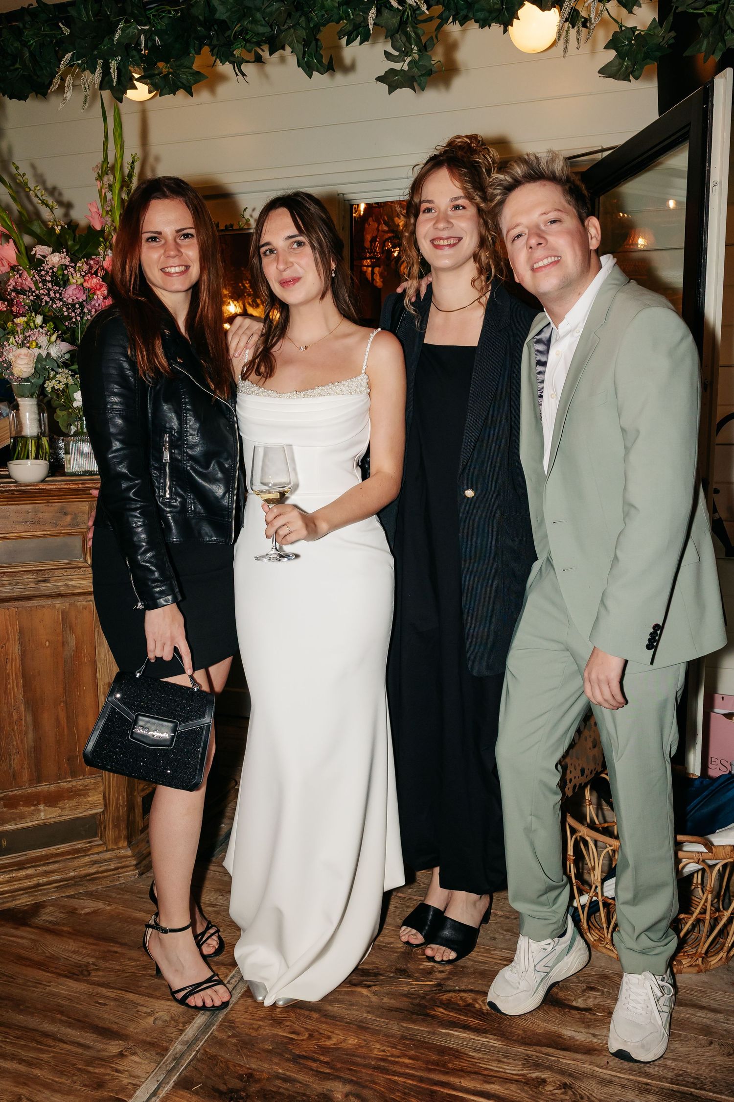 Bride in white gown posing with three guests at an elegant floral wedding reception.