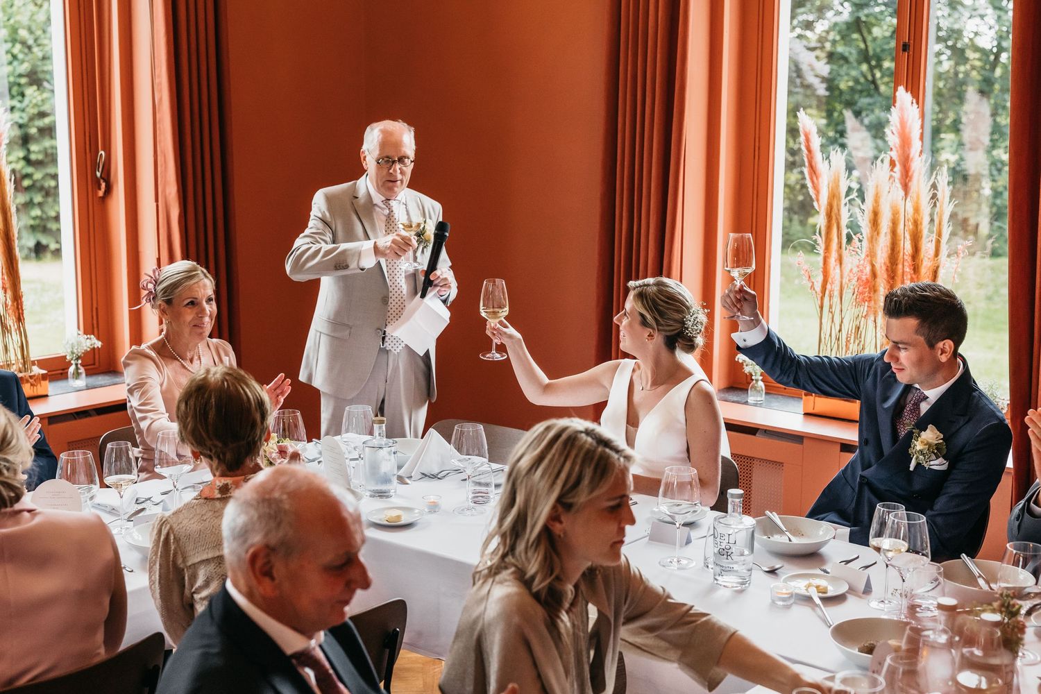 Father of bride gives champagne toast at elegant wedding reception dinner table.