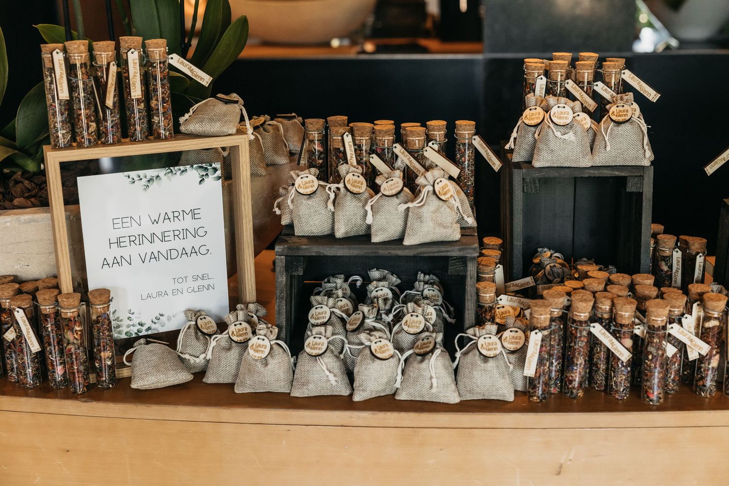 Rustic wedding favor table featuring cork-topped herb tubes and linen sachets with a Dutch keepsake sign.