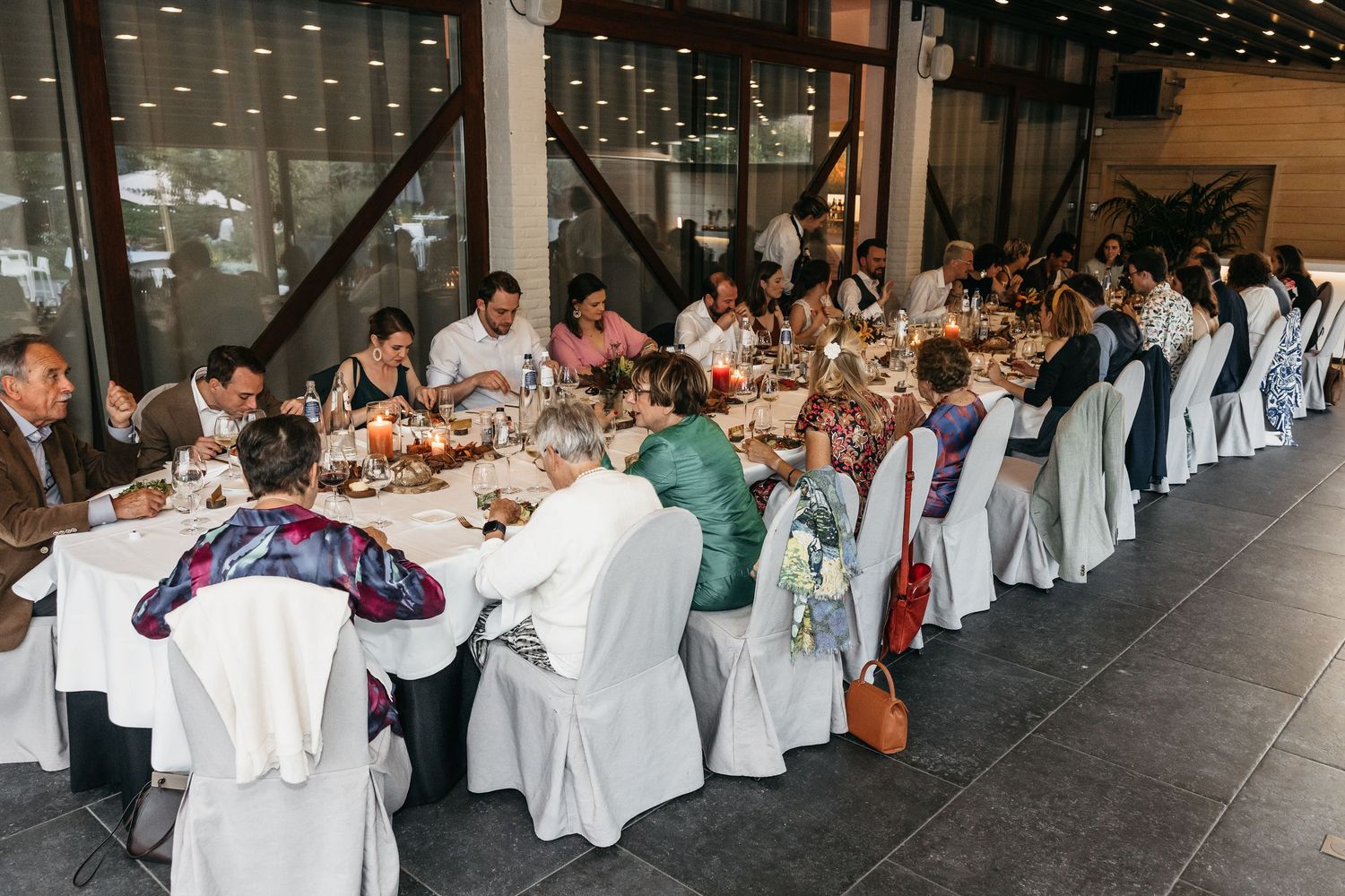 Guests seated at a long banquet table during a wedding reception dinner in a modern venue.