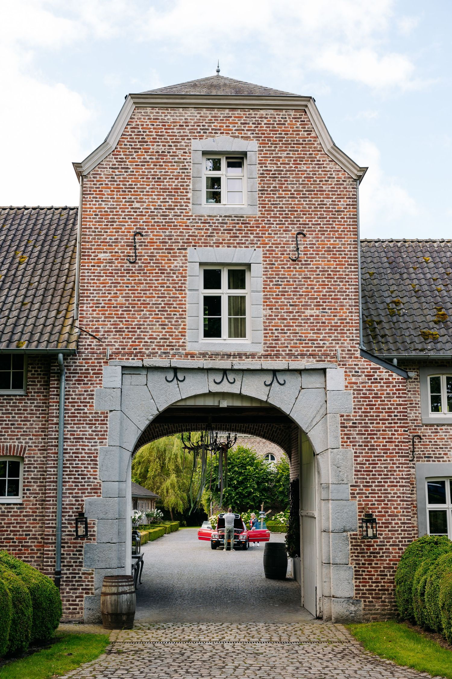 Historic red brick gatehouse with arched stone entrance leading to a courtyard garden.