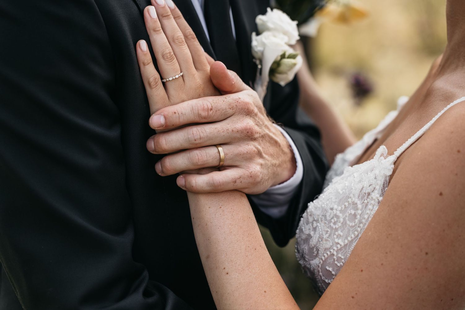 Close-up of bride and grooms hands showing matching gold wedding bands on their wedding day.