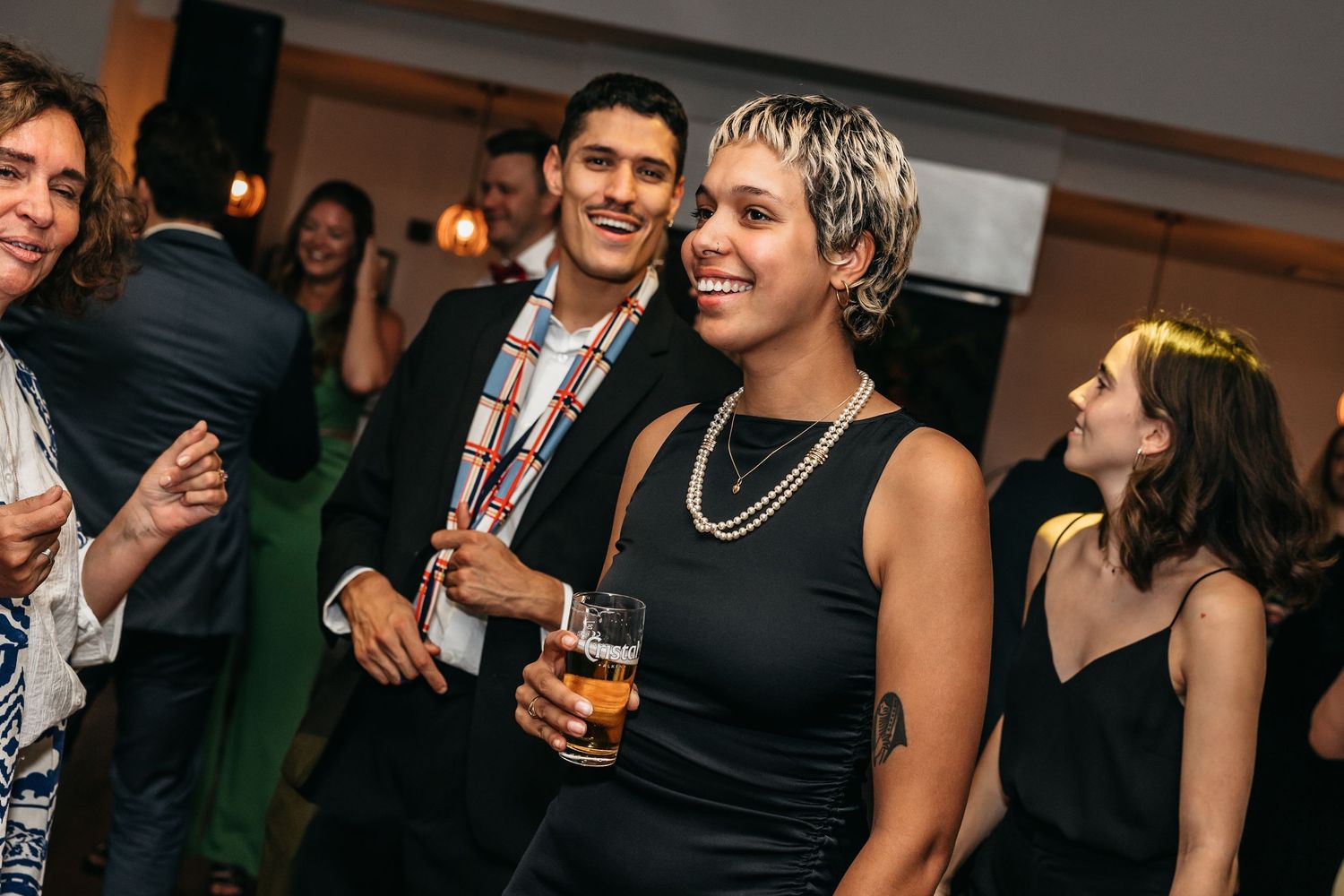 Couple smiling and holding drinks at elegant wedding reception party.