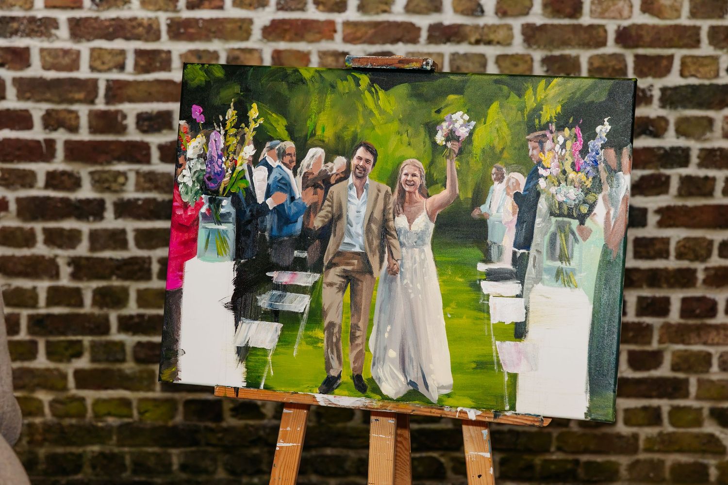 Live wedding painting on easel showing bride and groom ceremony in garden setting.