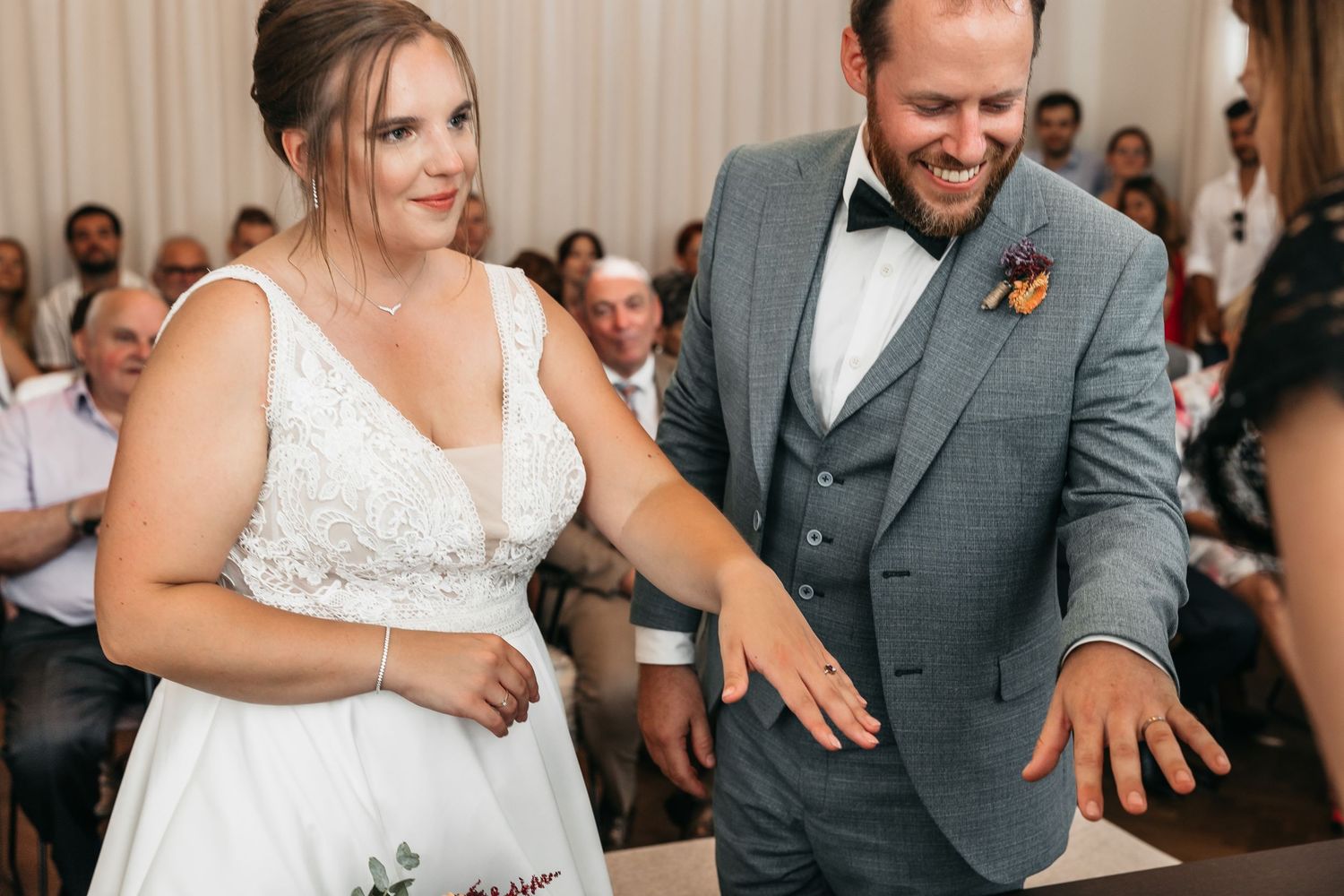 Bride and groom laugh together showing off their new wedding rings during their ceremony.