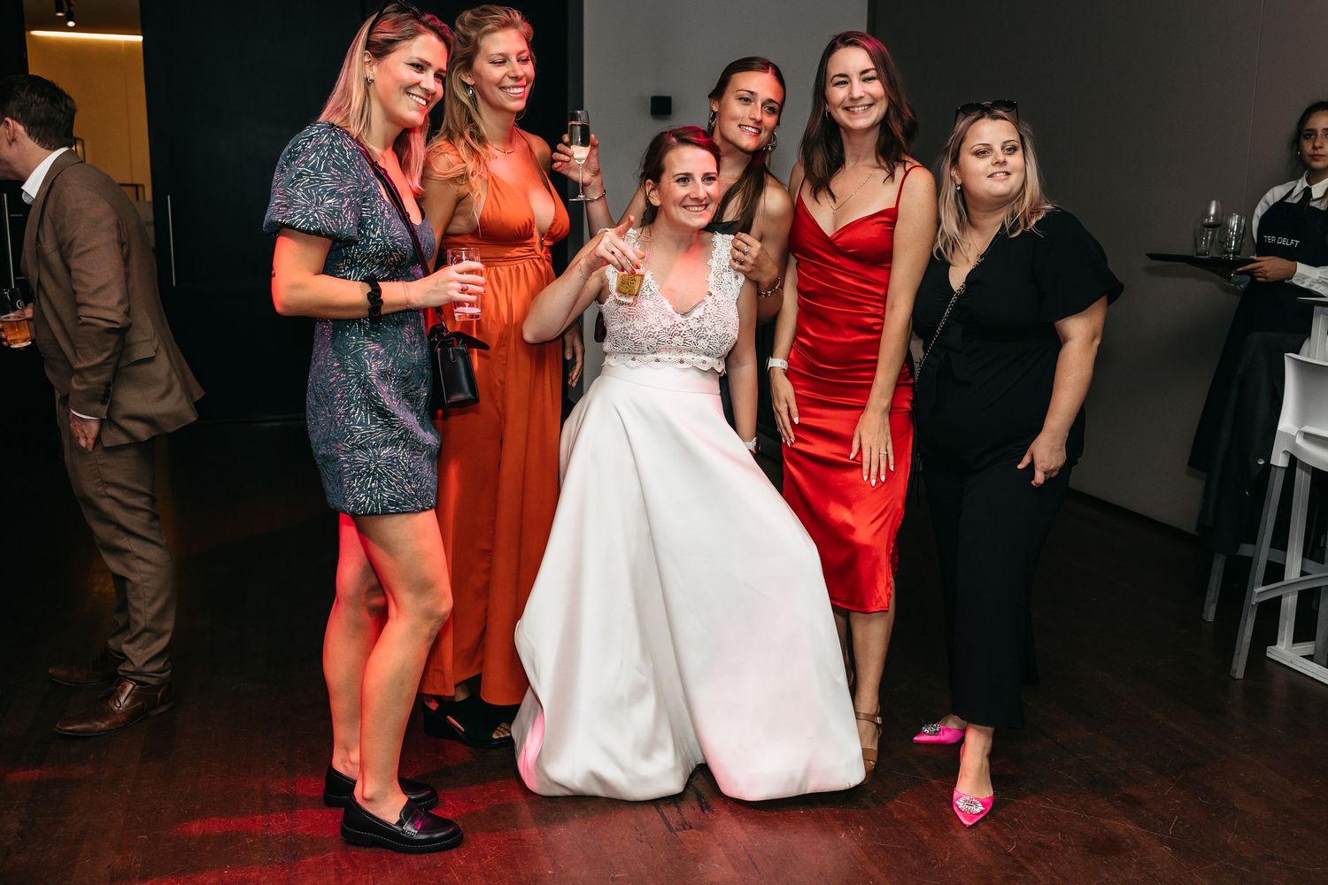 Bride in white gown posing with five bridesmaids at wedding reception.