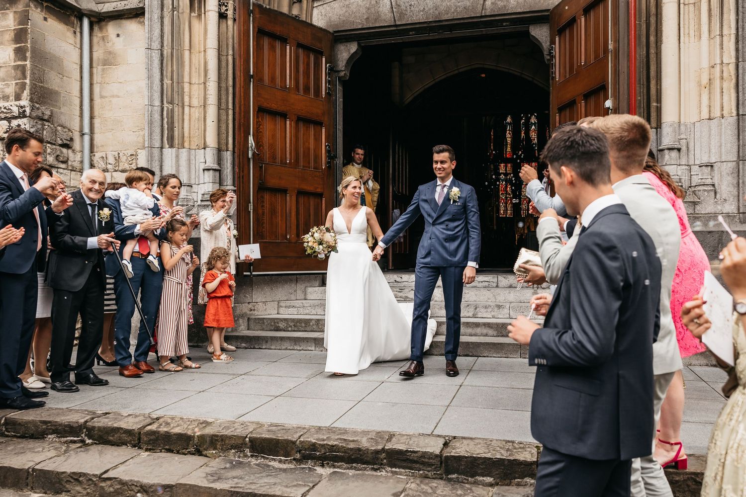 Newlyweds exit church doors as guests celebrate their marriage.