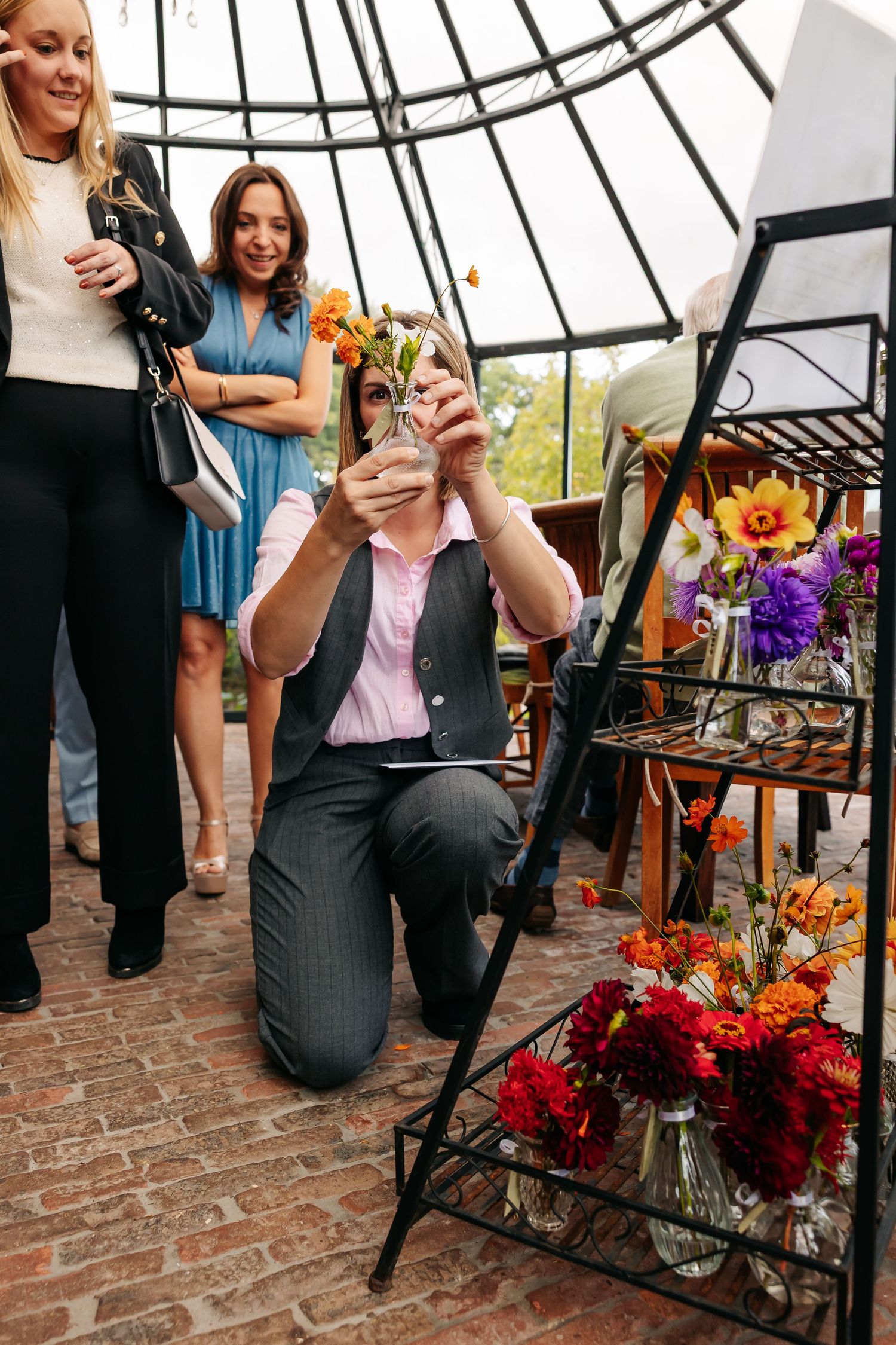 Man kneeling to photograph flowers in vase at colorful floral display at wedding.