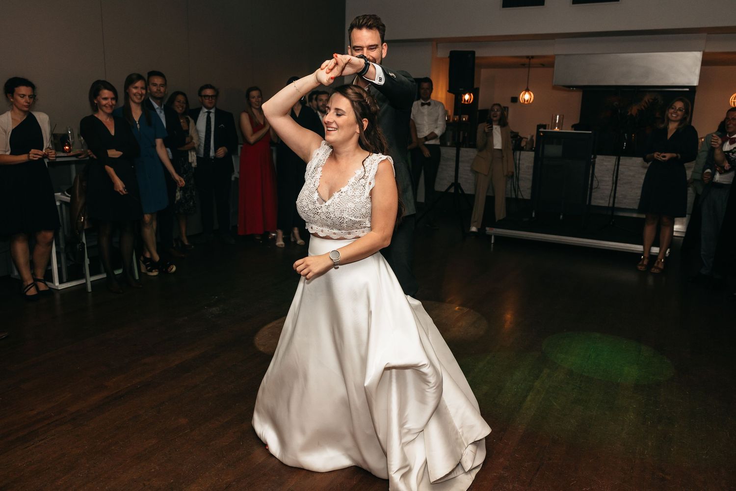 Groom spins bride in elegant white gown during wedding reception first dance.