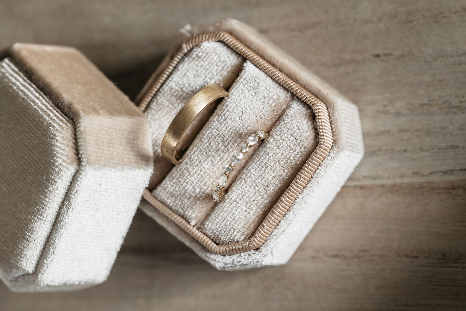Gold wedding band and diamond engagement ring displayed in a velvet ring box.