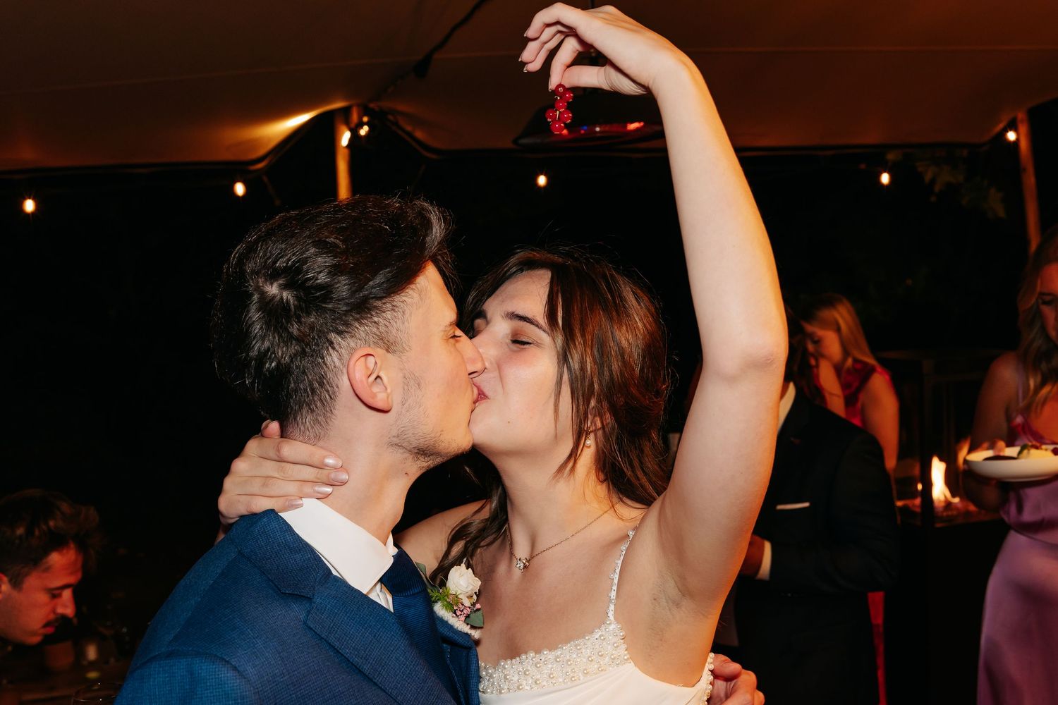 Bride and groom sharing romantic kiss on dance floor during wedding reception celebration.