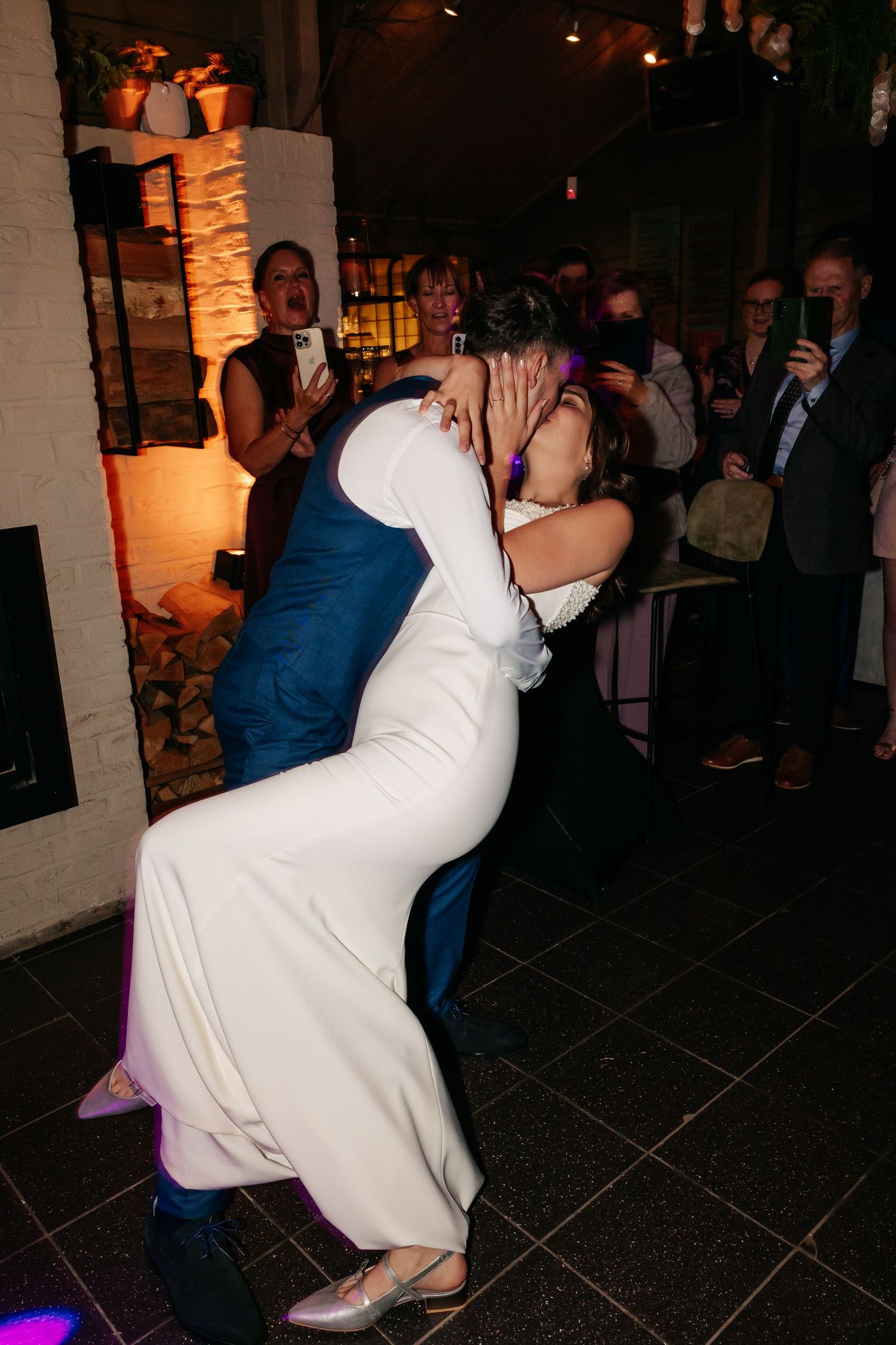 Groom dipping bride for a kiss on the dance floor at their wedding reception.