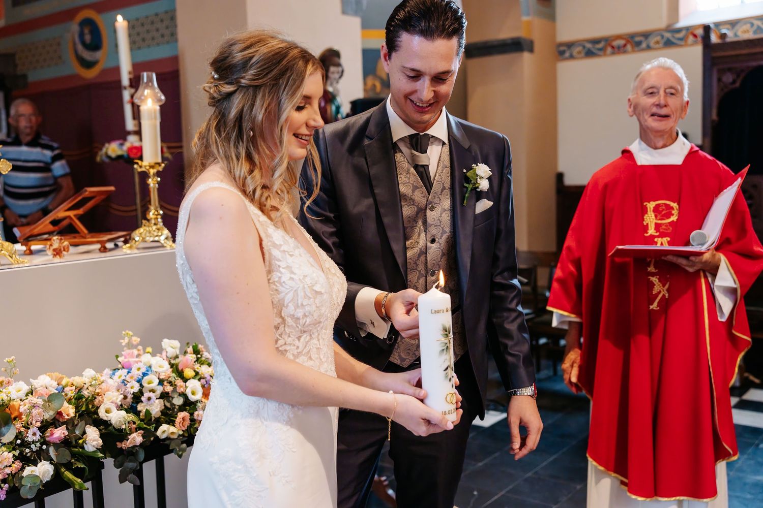 Bride and groom lighting unity candle together during church wedding ceremony.