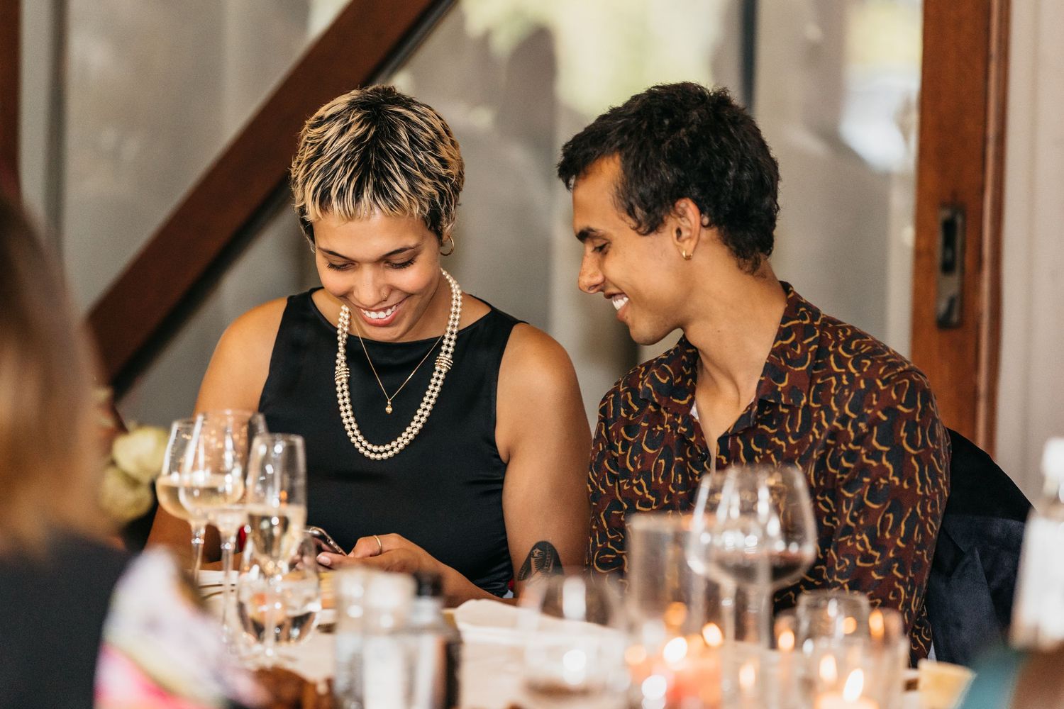 Smiling couple sharing a joyful moment together at a formal wedding reception dinner table.