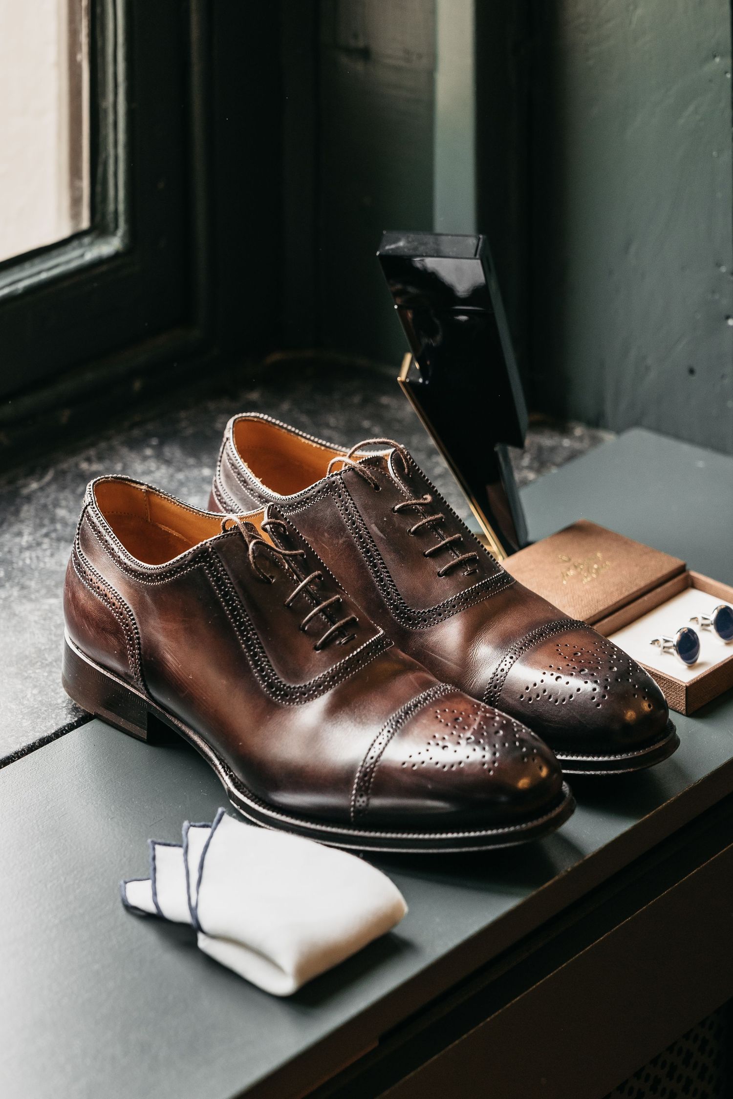 Brown leather Oxford brogue shoes with white socks and cufflinks for a groom.