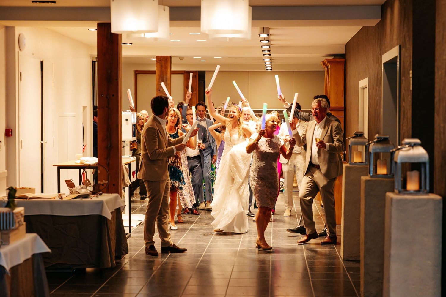 Bride and groom exit through a tunnel of glowing lightsabers held by cheering wedding guests.