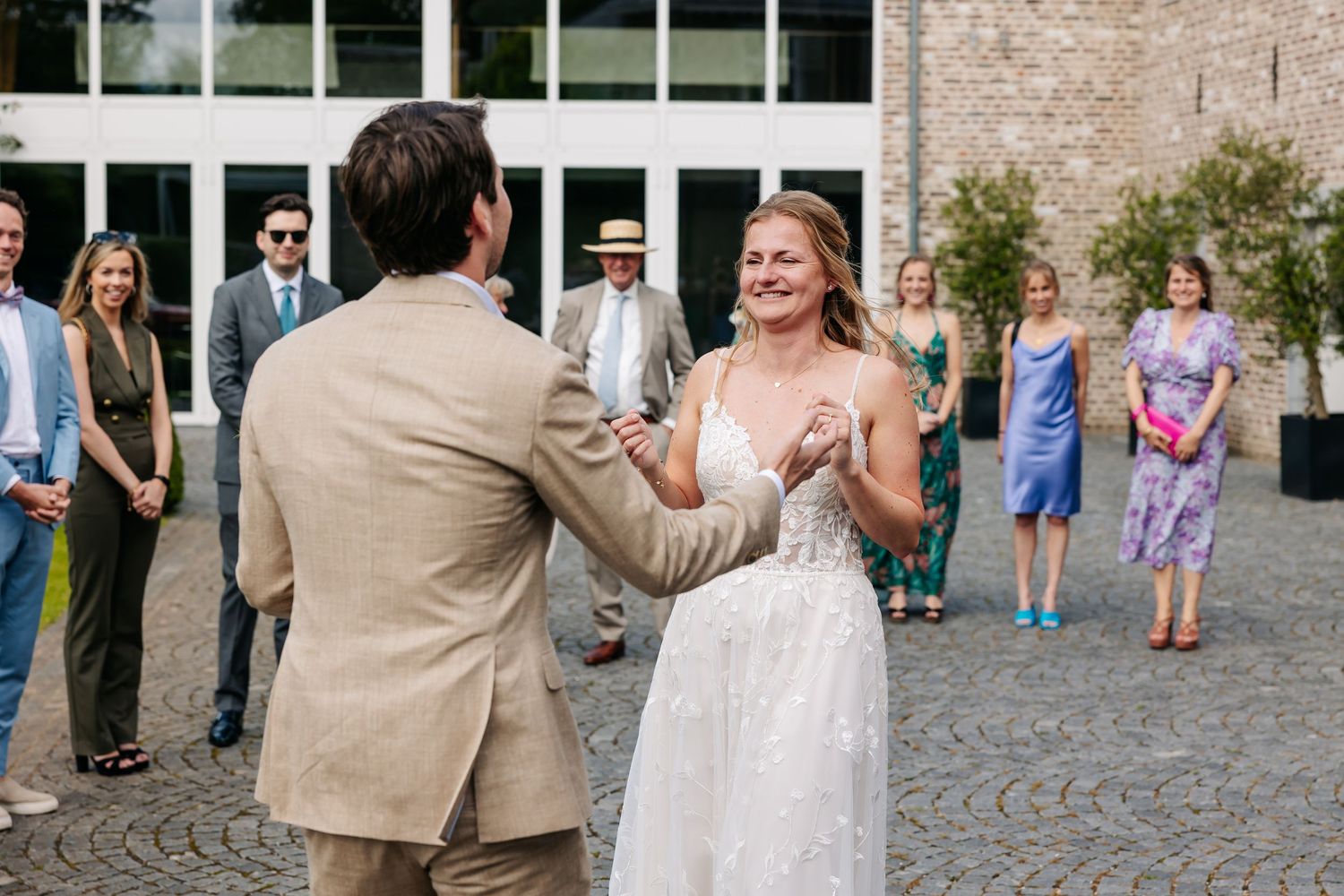 Bride and groom sharing joyful first look moment surrounded by wedding guests outdoors.