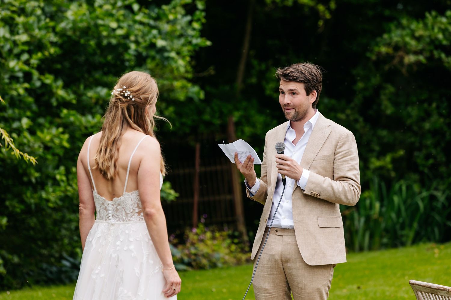 Groom reads heartfelt wedding vows to his bride during an intimate outdoor garden ceremony.