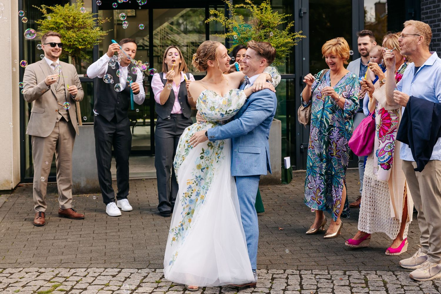 Bride and groom share first dance outside as guests blow bubbles at their wedding.