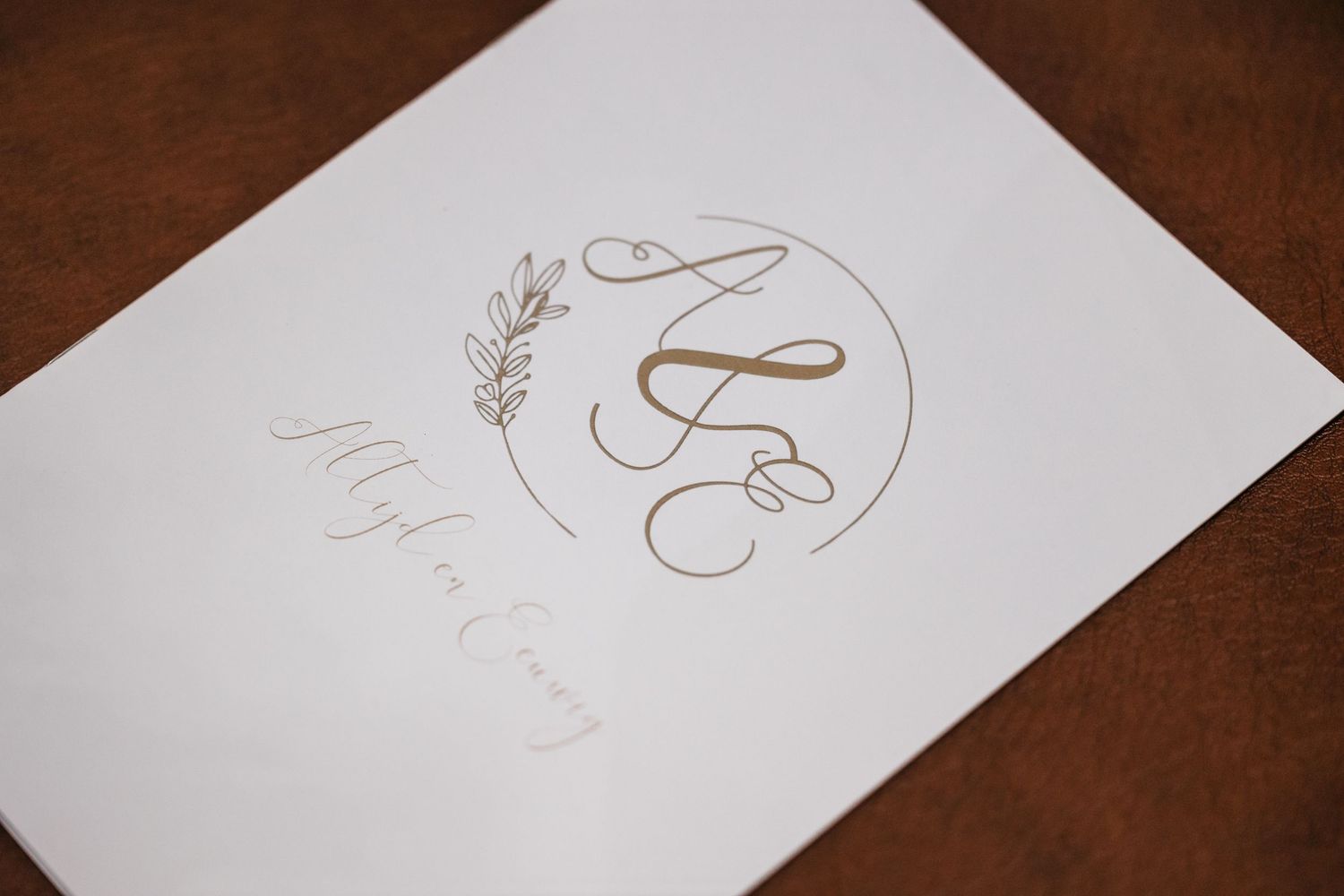 Elegant wedding stationery with gold monogram and floral design on white paper.