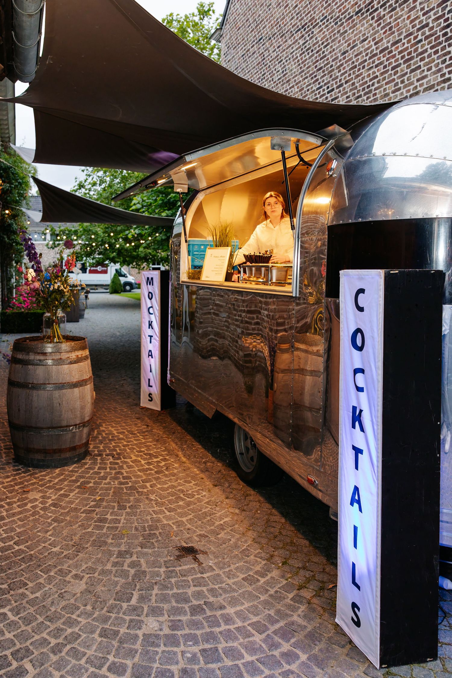 Vintage silver Airstream cocktail bar trailer lit up at night at an outdoor wedding venue.