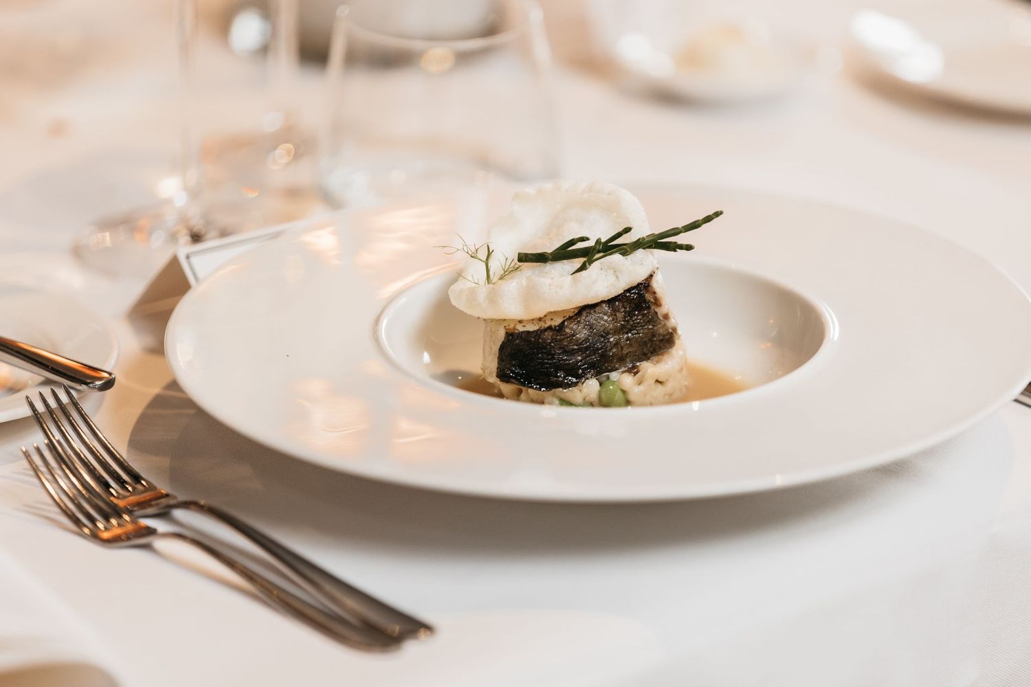 Elegant wedding reception dish featuring a gourmet fish fillet with cream sauce served on white plate.