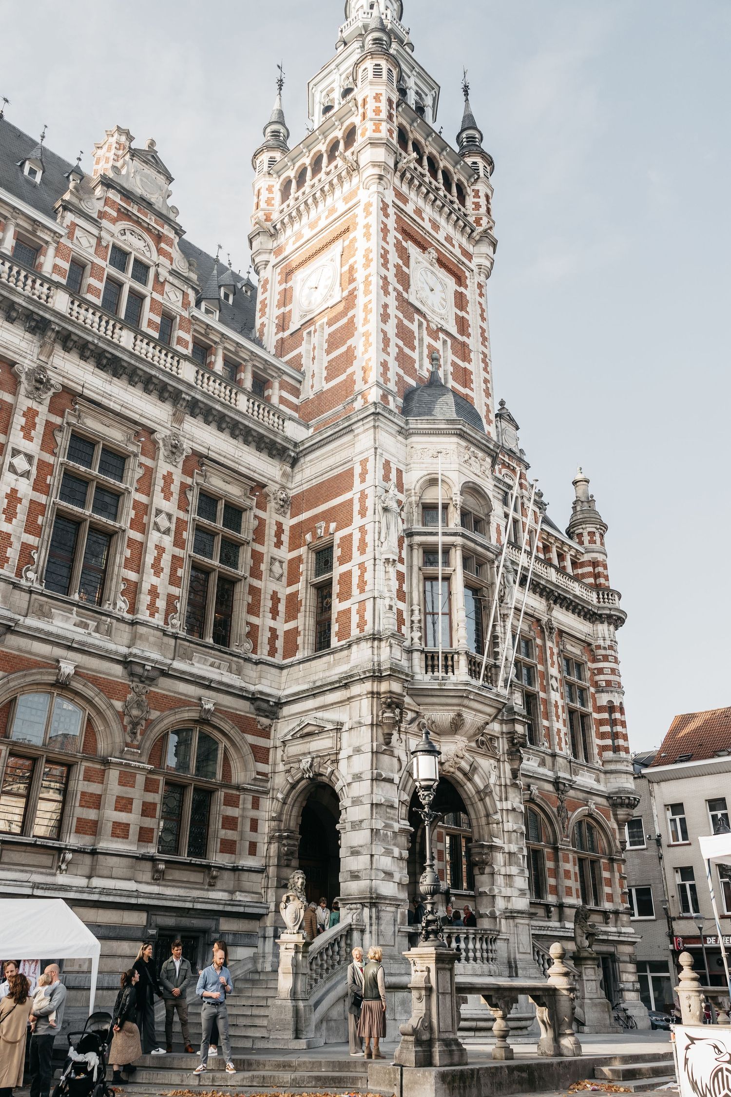 Ornate historic brick building with clock tower and decorative stonework under a cloudy sky.