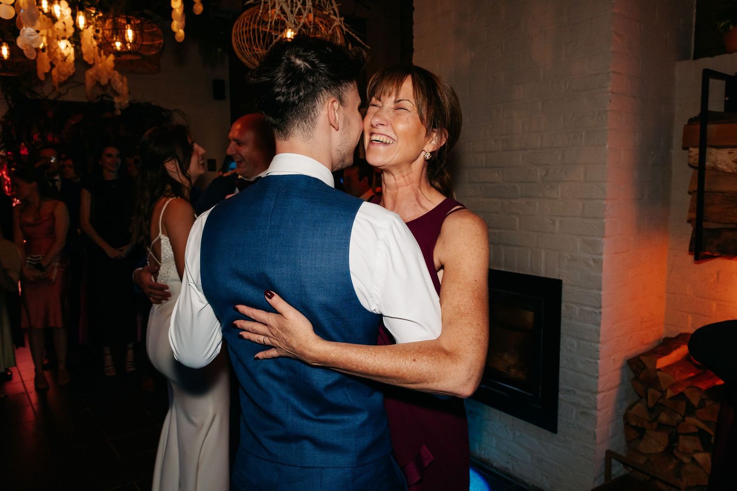 Groom dancing warmly with a woman in burgundy dress at wedding reception.