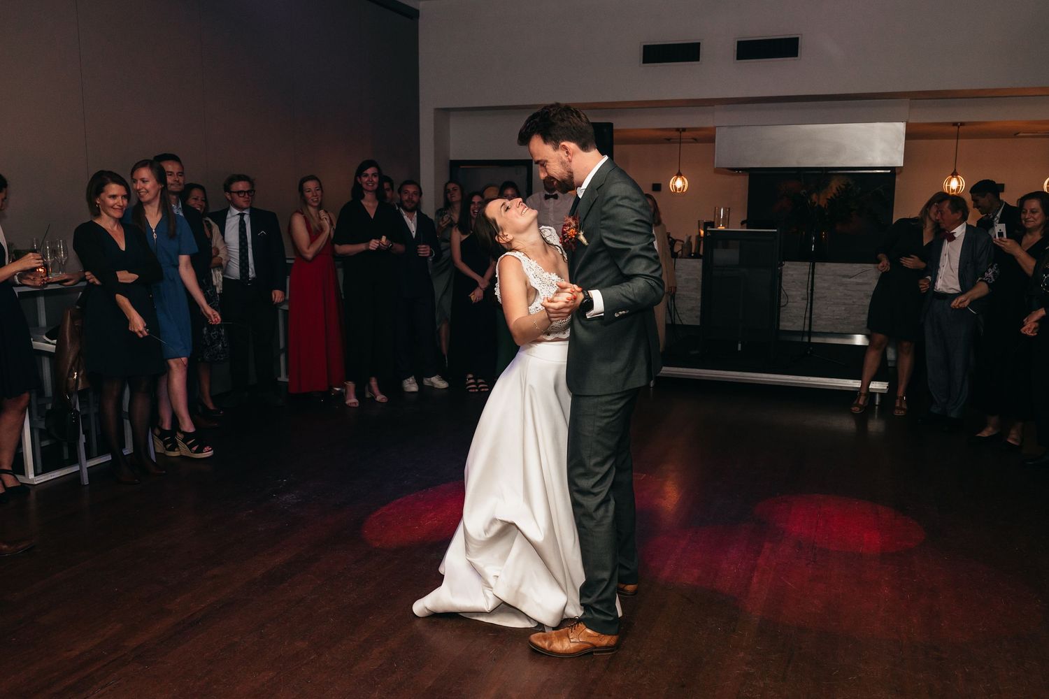 Bride and groom share their first dance at wedding reception while guests watch.