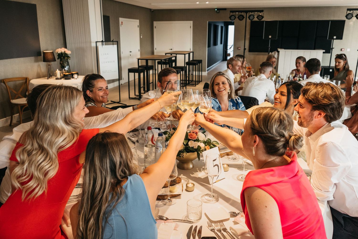 Wedding guests raising glasses in a celebratory toast around a beautifully decorated dining table.