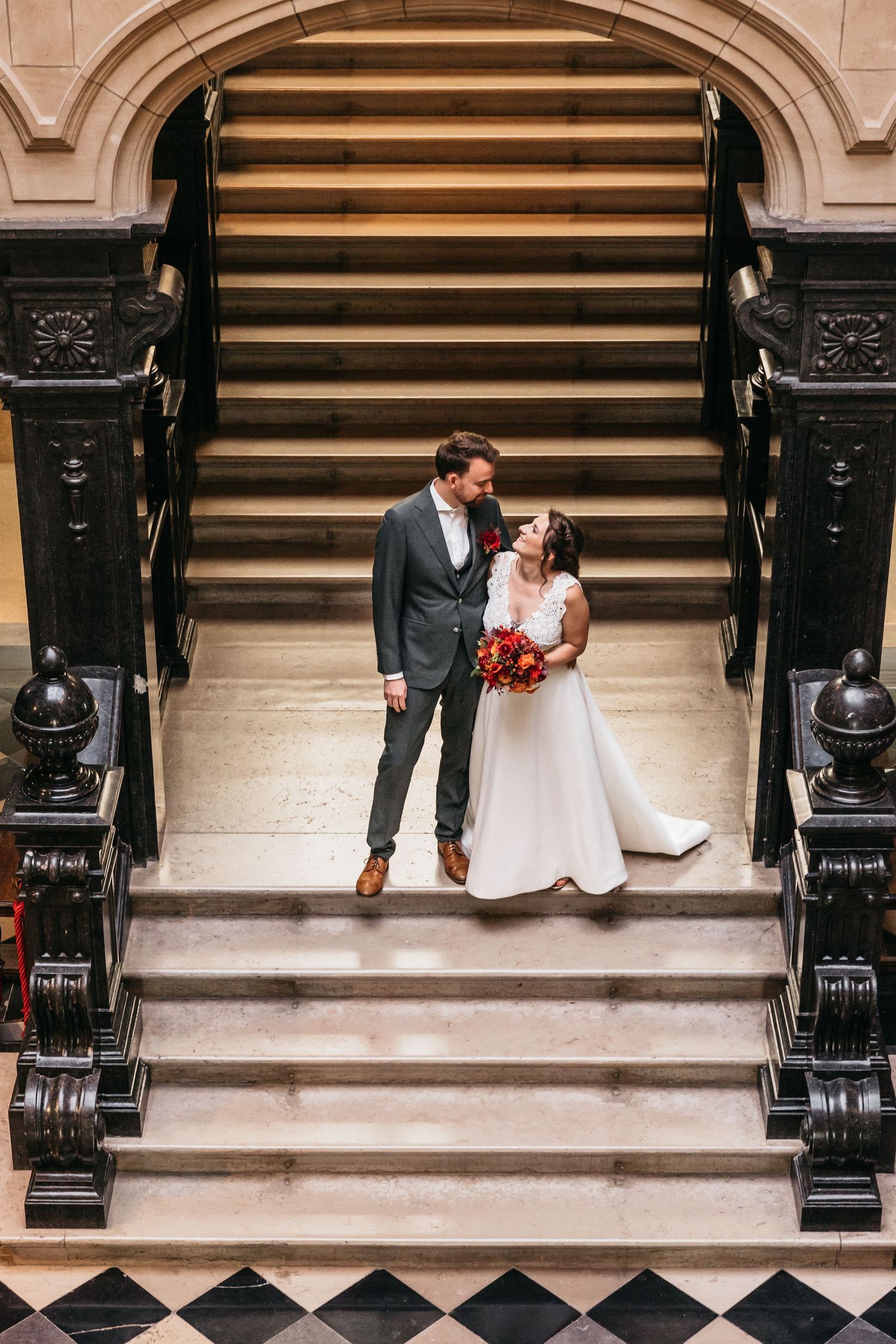Bride and groom share a romantic moment on grand staircase.
