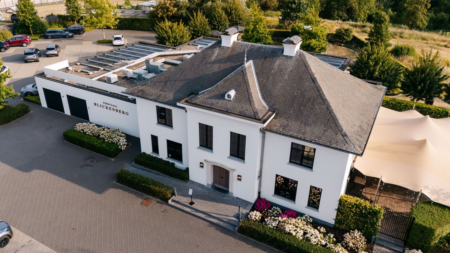 Aerial view of elegant white wedding venue building with parking area.