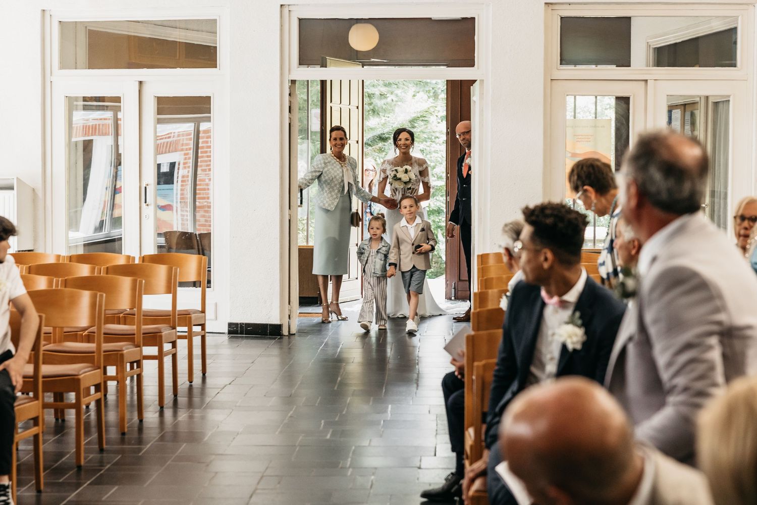Wedding guests walk down church aisle as ceremony begins in modern chapel.