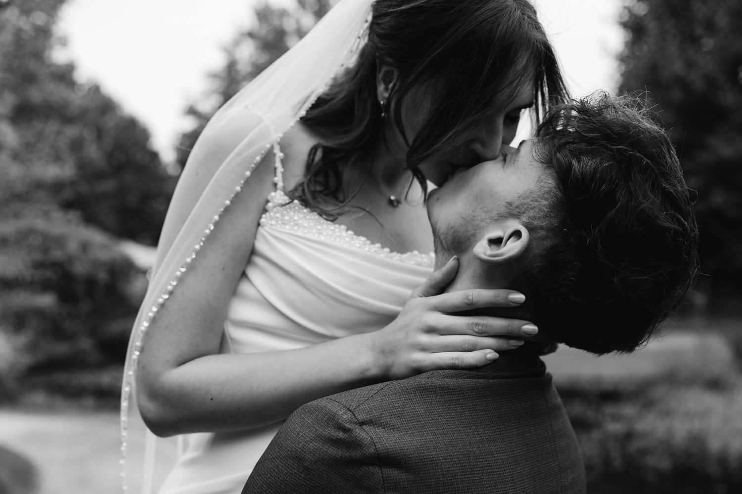 Black and white photo of bride and groom sharing an intimate kiss at their wedding.