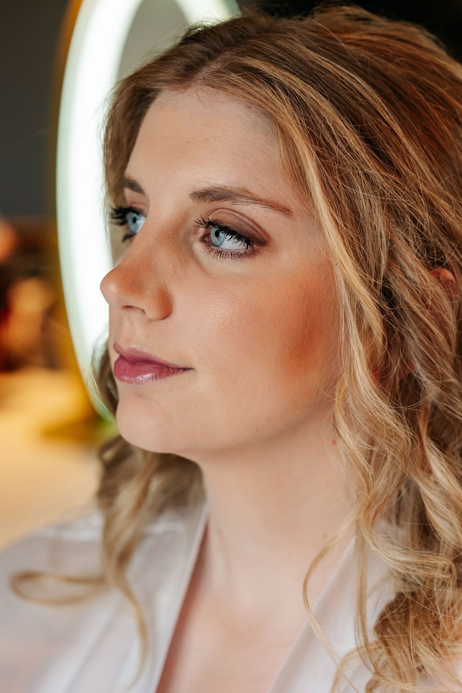 Close-up portrait of a bride with blue eyes and soft glam makeup in a white robe.