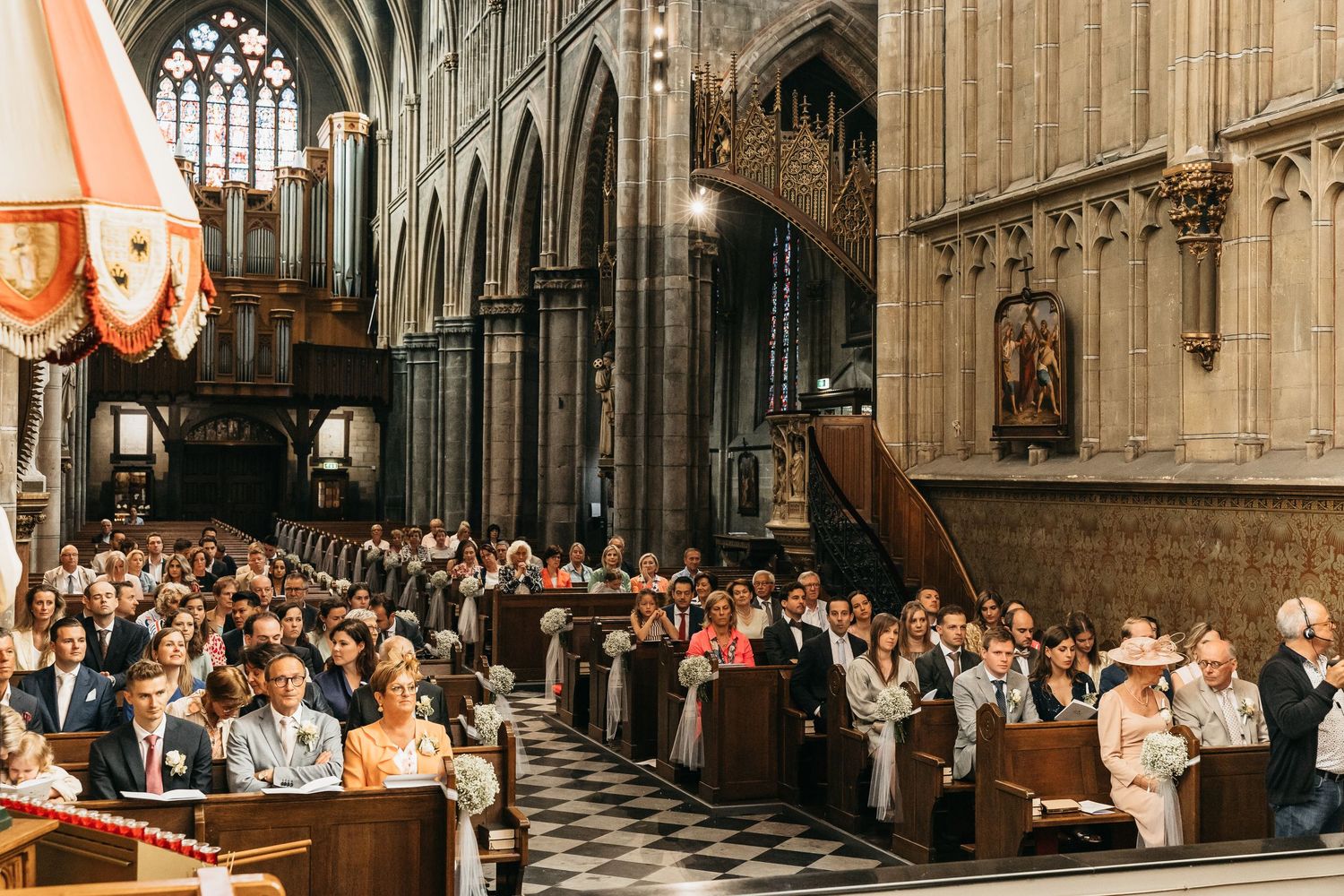 Wedding guests fill historic gothic cathedral pews during traditional church ceremony.