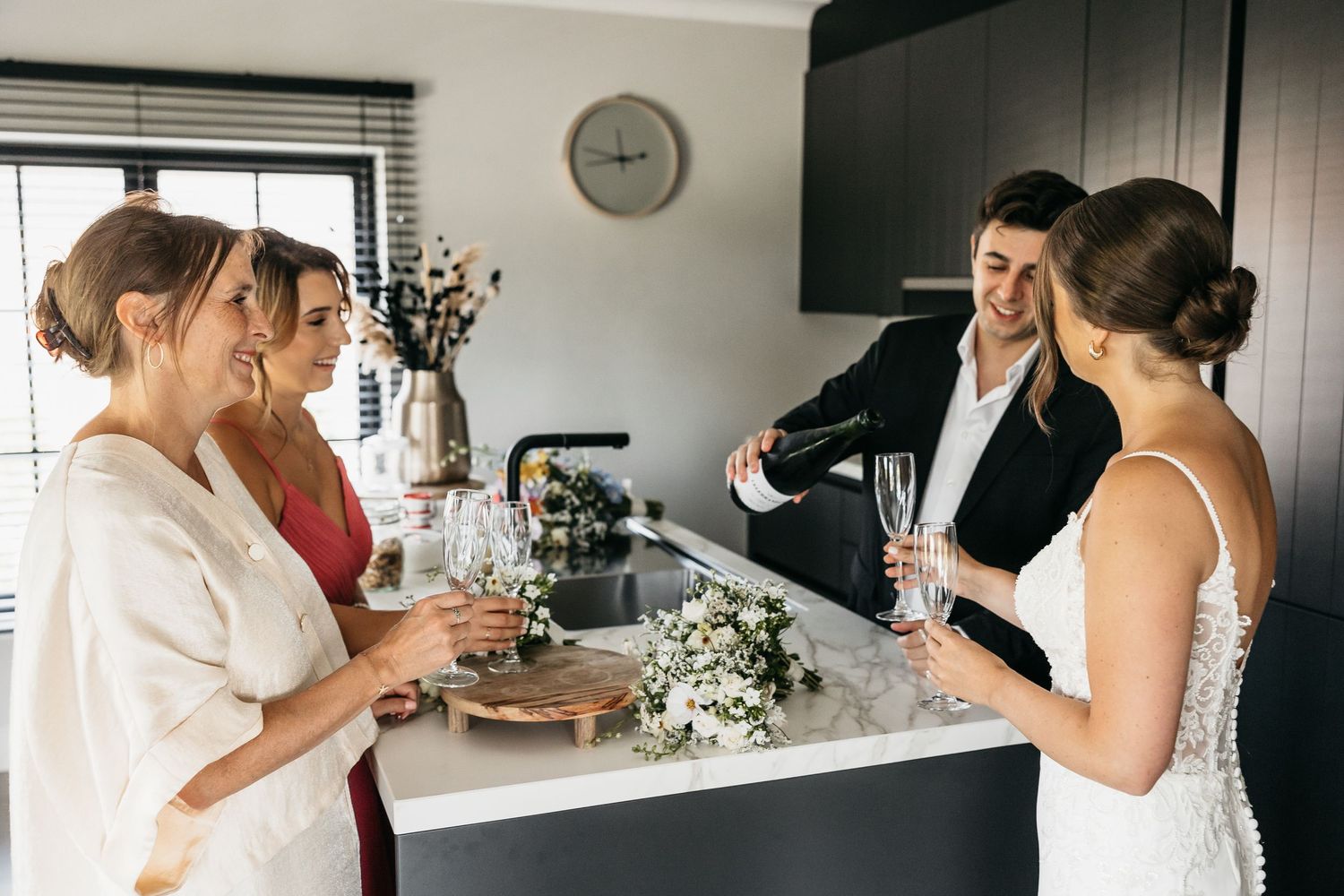 Wedding party celebrating with champagne in modern kitchen before the ceremony.