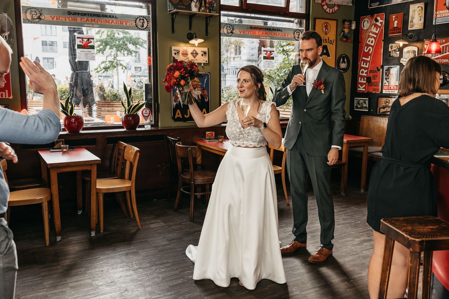 Bride and groom making entrance into decorated bar restaurant welcomed by cheering wedding guests.