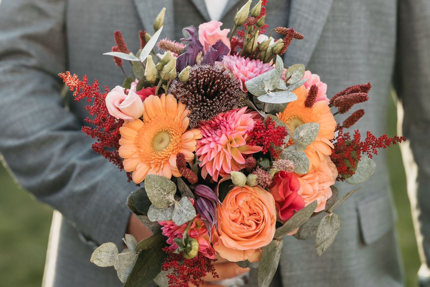 Detailed close-up of a colorful bridal bouquet with orange gerberas, roses, and dahlias.