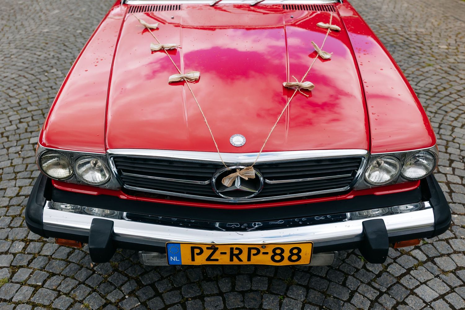 Front view of a decorated red classic Mercedes convertible with Dutch license plate PZ-RP-88.