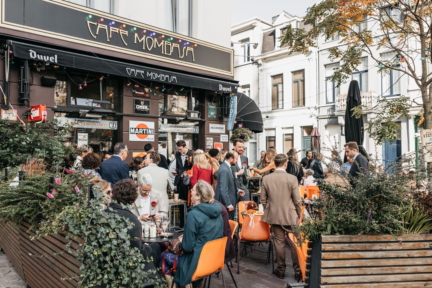 Busy outdoor cafe terrace with people socializing at Cafe Momma on a sunny day.
