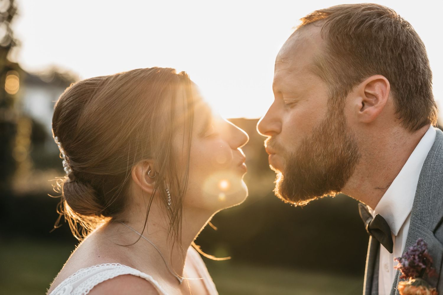 Bride and groom sharing a romantic almost-kiss bathed in warm golden sunset light.