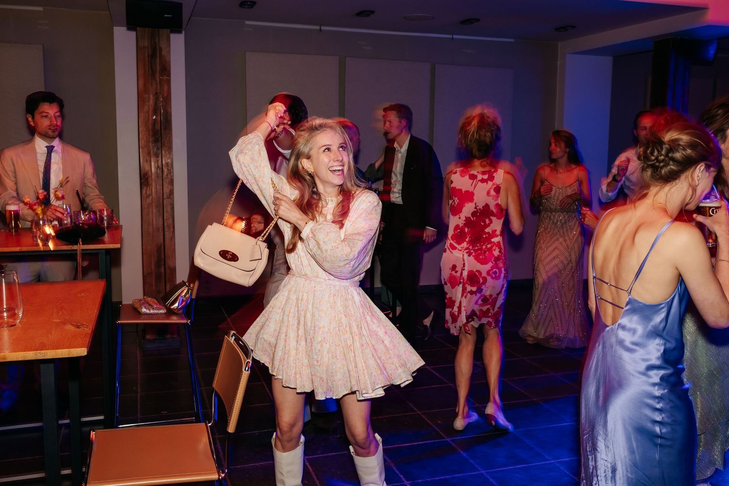 Young woman in white dress and boots dancing joyfully at a wedding reception party.