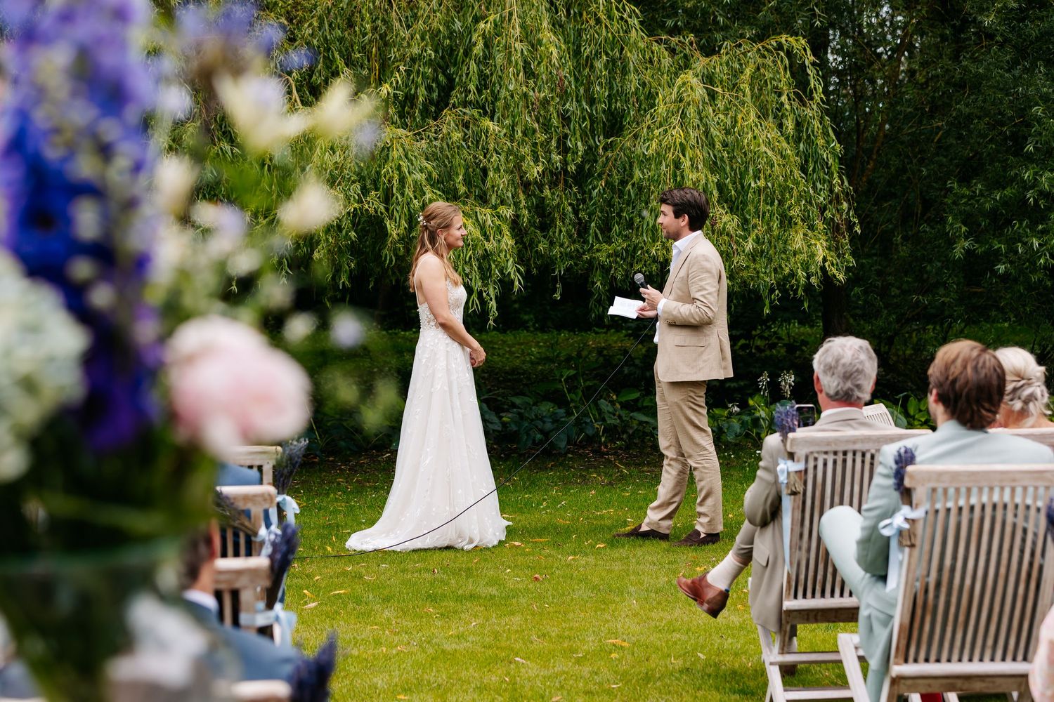 Bride and groom exchange vows outdoors during an intimate garden wedding ceremony with seated guests.