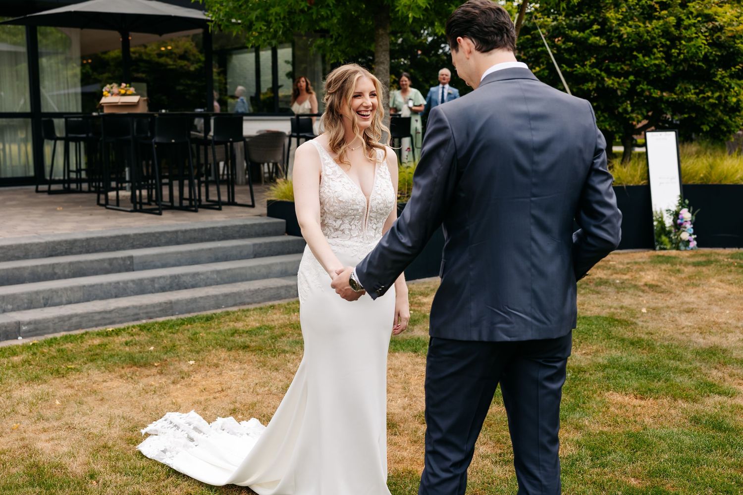 Bride and groom sharing a joyful first look moment on green lawn at outdoor wedding venue.